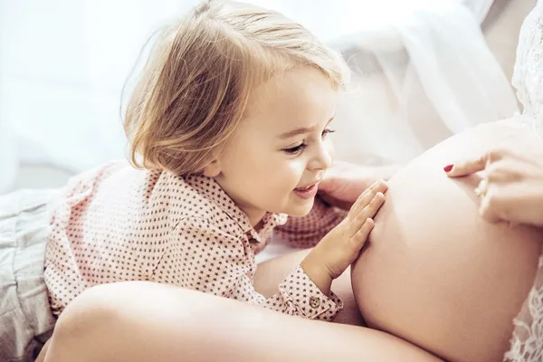 Criança acariciando a barriga da mãe grávida