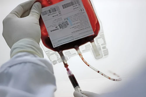 Pesquisador retirando sangue de uma bolsa de sangue